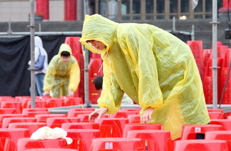 前第一夫人周美青在紙風車演出前,穿著小飛俠雨衣幫忙排椅子。(圖:取材自張大魯臉書)