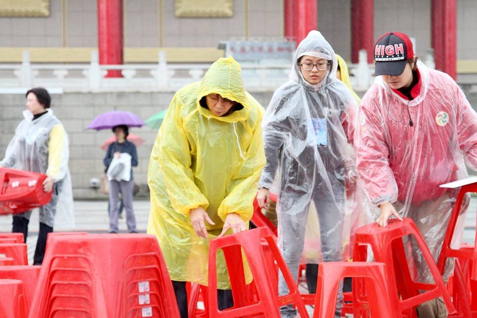 前第一夫人周美青在紙風車演出前,穿著小飛俠雨衣幫忙排椅子。(圖:取材自張大魯臉書)