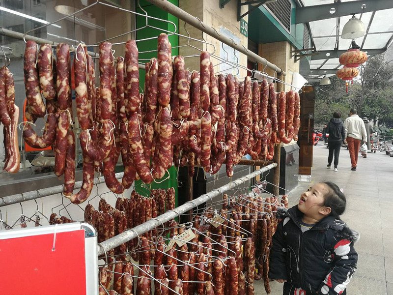 非洲豬瘟病毒耐性極強，可存活於冷藏豬肉100天、冷凍豬肉1000天，疫區豬肉、肉製品都將成為傳播途徑並感染豬隻。圖為上海商家在市場販售豬肉香腸，引來孩童垂涎。