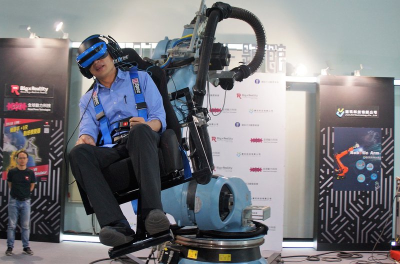 107年高雄資訊月場27日起正式開幕，高雄市長韓國瑜（前）傍晚前往參觀，並實地坐上機械手臂式VR體感機，感受最新體感科技。