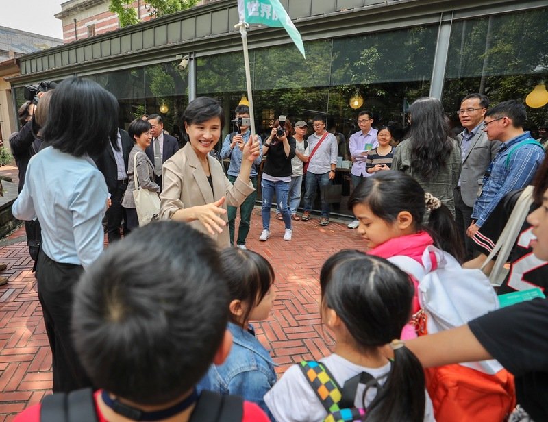 2019世界閱讀日啟動記者會17日在台北舉行，現場並安排走讀活動，由導覽員解說園區樟腦工廠的故事，文化部長鄭麗君（舉旗者）邀請路過學童一起參與。