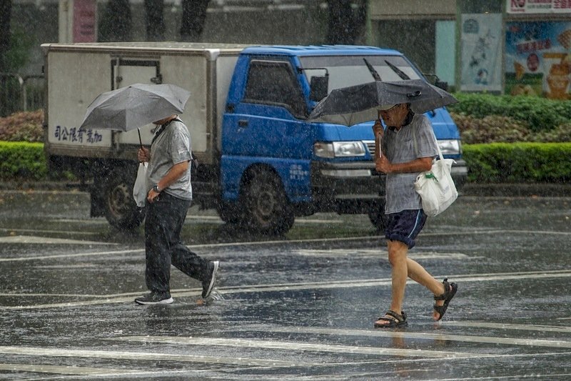 強烈颱風利奇馬來襲，台北市9日上午出現間歇性降雨，民眾外出撐傘防風雨。(圖：中央社)