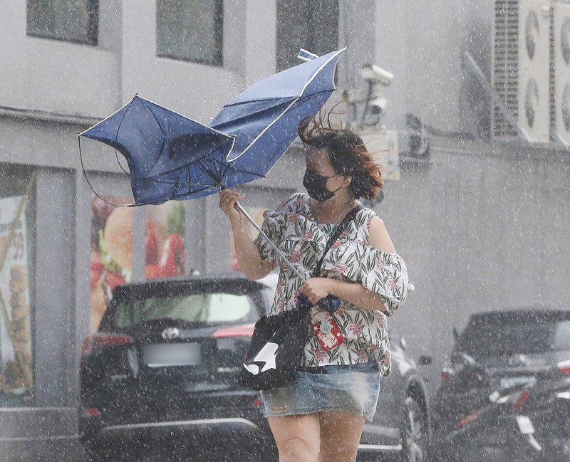 颱風利奇馬目前已減弱成中颱，且因路徑偏移，對台灣地區影響降低，不過台北市區9日還是有間歇性風雨，突發強風讓路上行人的傘具開花。