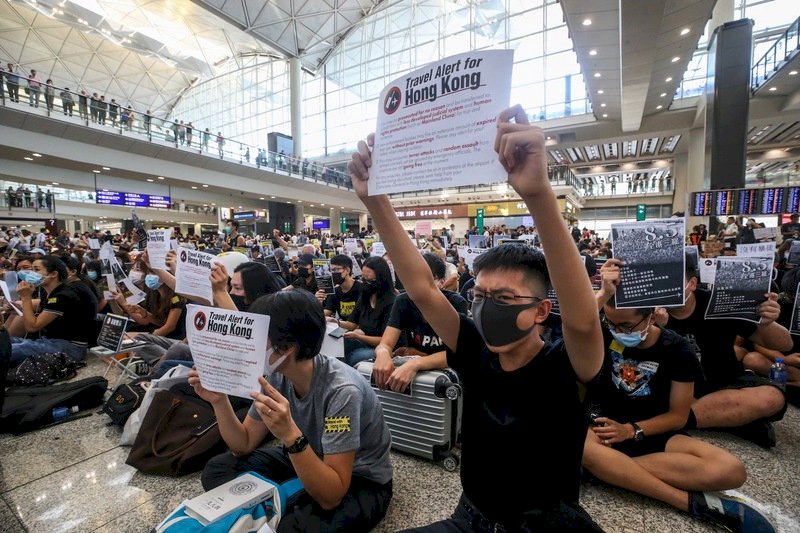 香港國際機場9日有「反送中」集會，部分參加集會民眾在背部貼上不同語言的標語並向旅客展示，又向入境旅客派發不同語言的反修例小冊子和貼紙等，以行動表達立場及訴求。