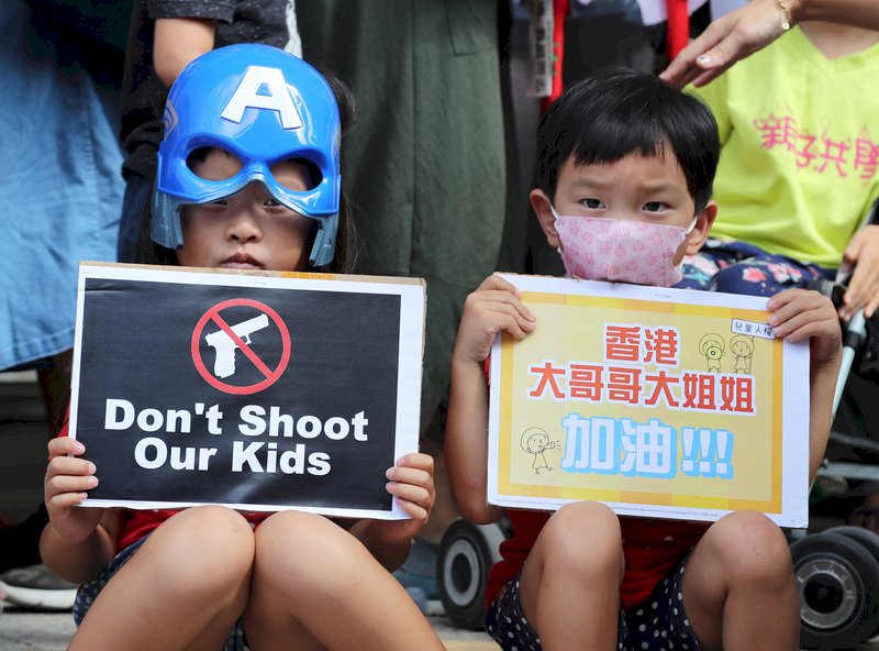 台灣親子共學教育促進會等民間團體8日發起「兒童連儂牆撐香港」活動，關注香港兒童人權議題，持標語高喊「Don't shoot our kids」。