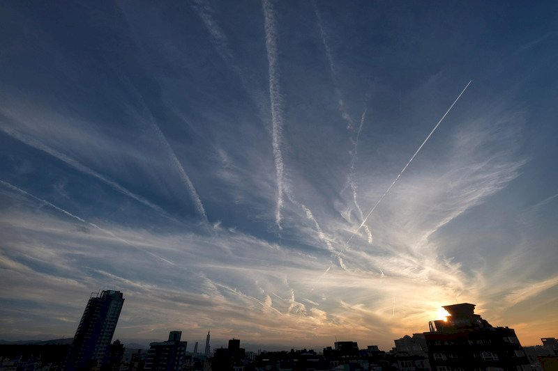 台北市4日傍晚天空出現不少俗稱「飛機雲」的凝結尾跡，是由飛機引擎排出的濃縮水蒸氣所形成的可見雲，在空中劃出道道白色條紋。