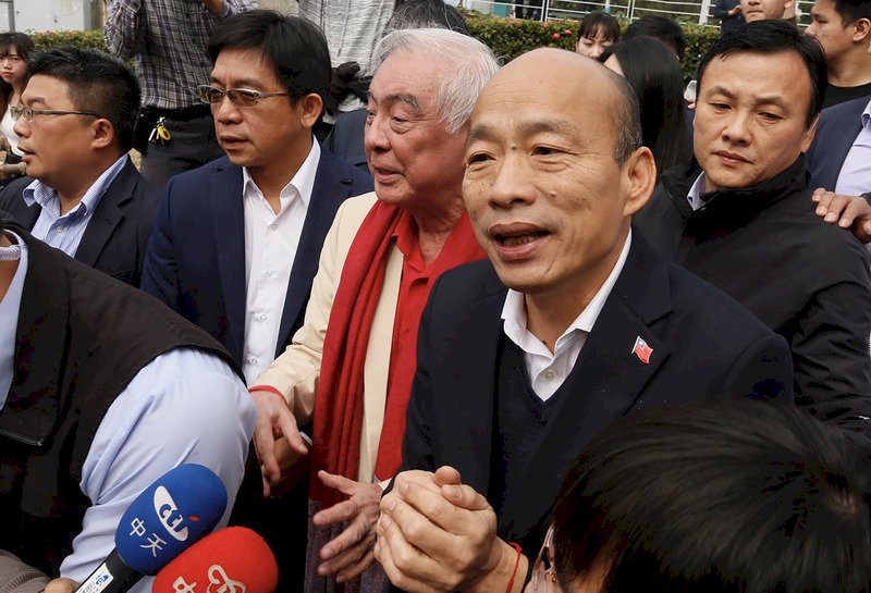 高雄市長韓國瑜(前右)21日出席公開活動時,面對媒體問及罷免危機與國民黨黨籍等相關議題時,僅簡單拱手致意,不發一語隨即離去。