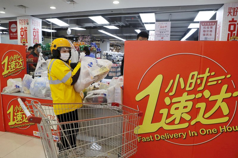 陸媒報導，武漢肺炎疫情期間，中國大陸冷凍食品網路銷售量爆增近20倍。圖為上海古北家樂福超市，外送員正在領取市民網路訂購的商品。疫情期間，家樂福客流量減少，但網路總銷售額成長3到4倍。（中新社提供）