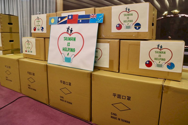 外交部15日舉行太平洋4友邦醫療口罩捐贈儀式，每個箱子上都貼有「台灣正在幫助」（Taiwan is helping）字樣，以及我國與邦交國的國旗。