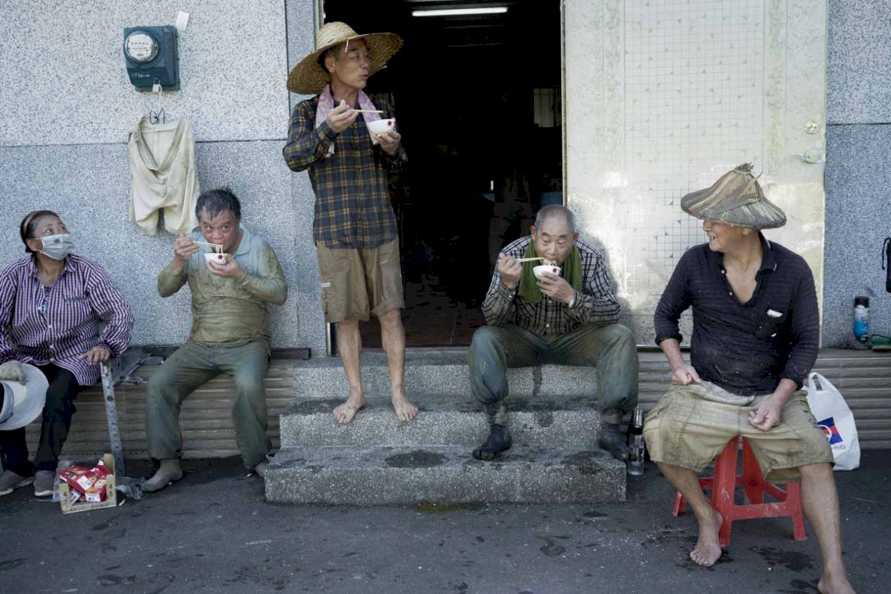 農友們從清晨五點多割到上午十點多，已經割了一大半，簡秋陽（右）招呼大家吃點心休息一下，由於換工割稻需要大量人力，也非常消耗體力，需要大量的食物補充體力，因此，吃「割稻仔飯」是割稻當天非常慎重的大事！簡秋陽準備豐盛菜飯招待換工農友，也藉此表達謝意。   圖：張良一/攝