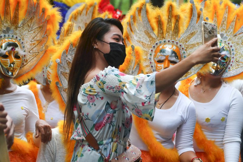台北市政府20日在台北街頭舉辦菲律賓面具嘉年華活動，邀民眾一同感受菲律賓特色文化活動，有民眾把握機會與遊行隊伍合影。