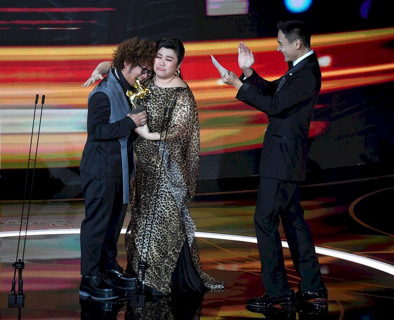 第57屆金馬獎21日晚間7時起在台北國父紀念館頒獎，藝人納豆（左）以電影「同學麥娜絲」奪得最佳男配角，上台時開心擁抱頒獎人林美秀（中）。