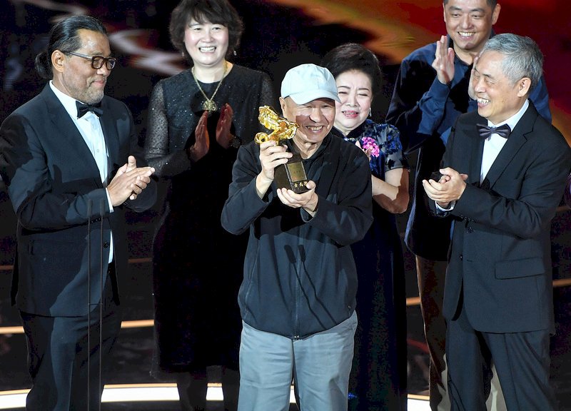 第57屆金馬獎21日晚間在台北國父紀念館舉行頒獎典禮，今年由導演侯孝賢（中）榮獲終身成就獎，他開心在台上接受各界喝采。