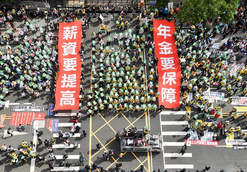 一年一度的勞工大遊行1日中午登場,今年活動號召逾3000人參與,民眾在立法院前拉開「薪資要提高」、「年金要保障」布條,表達期待立院「最低工資法」、「勞保年金改善方案」儘速審議通過的訴求。 (圖:中央社)