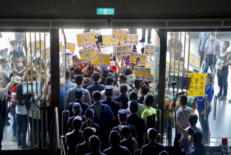 高雄市議會7日上午進行「高雄市環境污染防治作為」專案報告,民間團體「反空污反萊毒顧健康全民聯盟」到場外陳情,喊話要市長陳其邁出面,還作勢衝入議會遞交陳情書,但被警方攔下。 (圖:中央社)