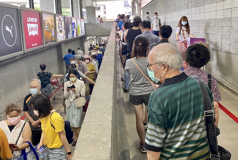 國內疫情持續升溫,美式賣場13日下午湧入大批民眾,大排長龍準備採買物資。 (圖:中央社)