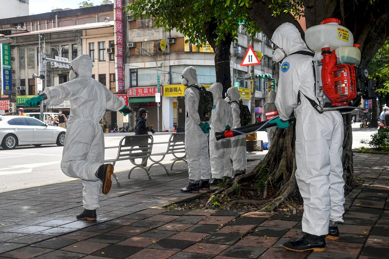 國內COVID-19疫情持續延燒，國軍化學兵2日上午前往台北市西寧市場執行消毒作業，離去前也互相幫忙彼此進行個人消毒。 (圖：中央社)