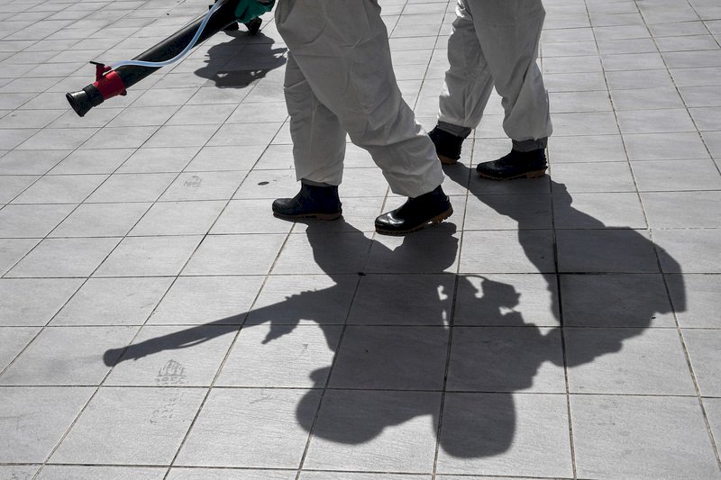 疫情延燒，國軍化學兵2日出動至台北市各區進行消毒，豔陽高照，國軍的影子被刻劃在地板上。 (圖：中央社)