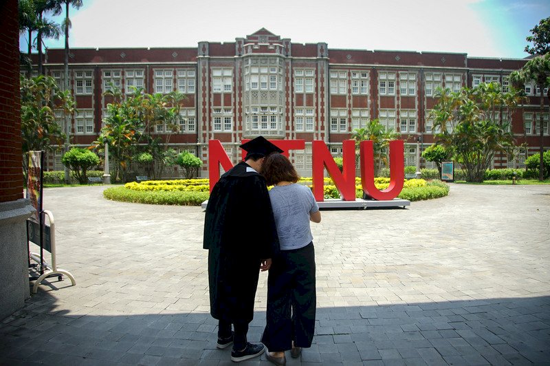 國內疫情嚴峻,許多學校畢業典禮都改成線上舉辦,台灣師範大學日前也舉行線上畢業典禮,20日一名畢業生穿著學士服到空蕩蕩的校園內拍照留念,疫情下少了同儕的畢業季,只剩家長相伴。 (圖:中央社)