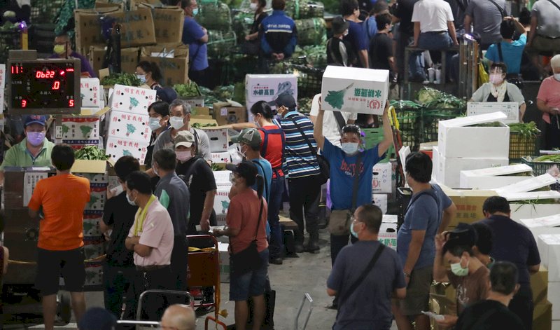 位於台北市萬大路的第一果菜批發市場,24日晨零時起,陸續有貨車抵達市場送、卸貨。市場內的承銷商、貨運司機等出示快篩陰性文件才進場,凌晨3點左右,工作人員開始展開喊價、販售。 (圖:中央社)