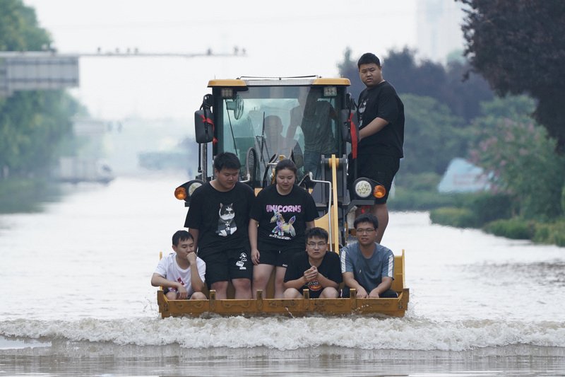 河南連日大暴雨。24日在河南新鄉市,民眾乘坐挖掘機通過新中大道一處涉水路段。(中新社提供) (圖:中央社)