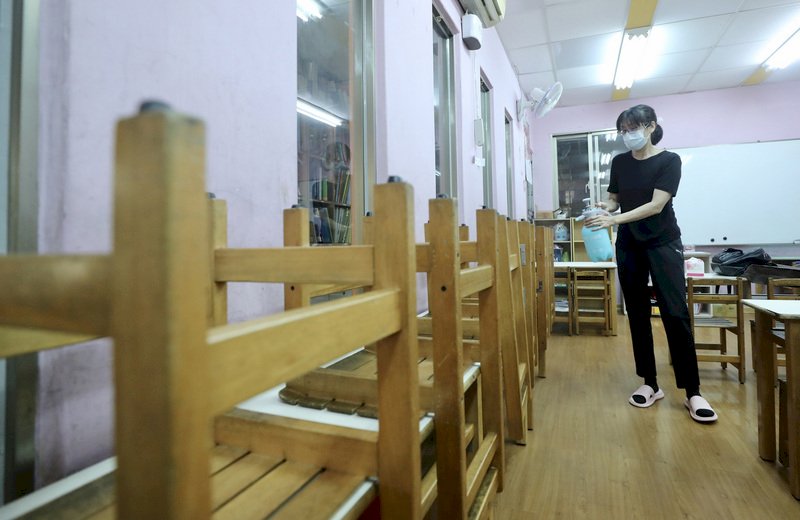 全國COVID-19(2019冠狀病毒疾病)疫情警戒7月27日到8月9日從三級降為二級,幼兒園、托嬰、課照中心跟補習班有條件式適度開放,26日安親班老師在教室消毒環境,做好各項防疫措施,準備開班復課。 (圖:中央社)