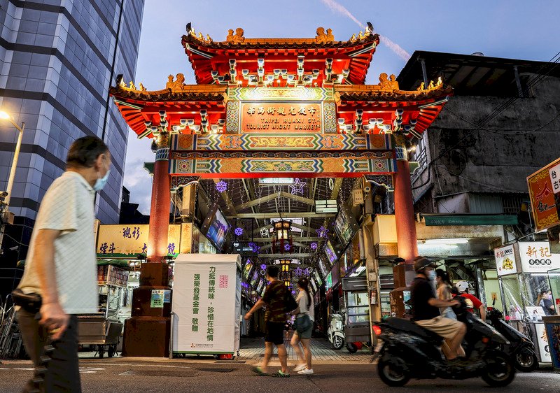 疫情警戒降級前一天,台北艋舺商圈夜市再出發,艋舺等5大夜市26日晚間復業,攤商紛紛回到街頭準備營業做生意,為落實防疫,自治會也在出入口進行消毒、測量體溫與實名制。 (圖:中央社)