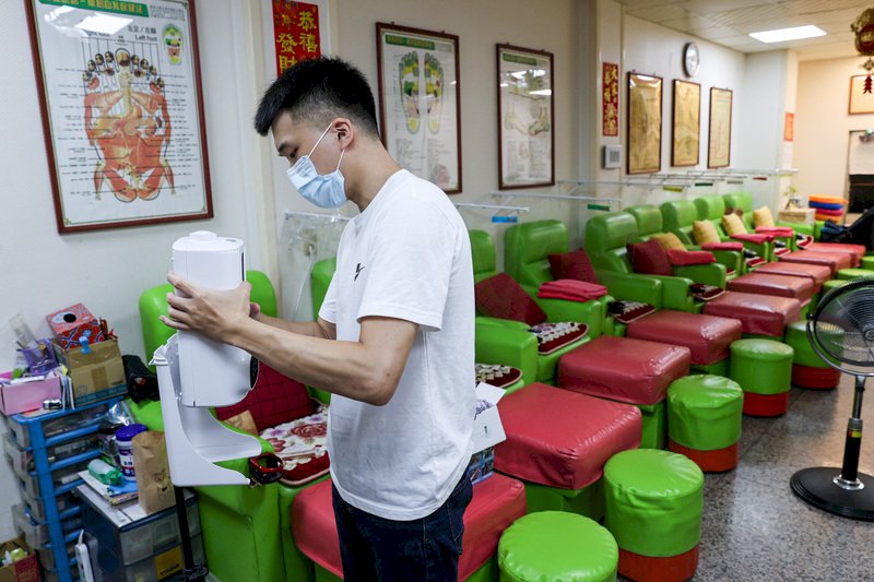 中央宣布27日全國疫情警戒降為二級,按摩業有條件開放。台北市萬華區的按摩業者上午架設酒精消毒機,做好防疫工作,準備開張做生意。 (圖:中央社)