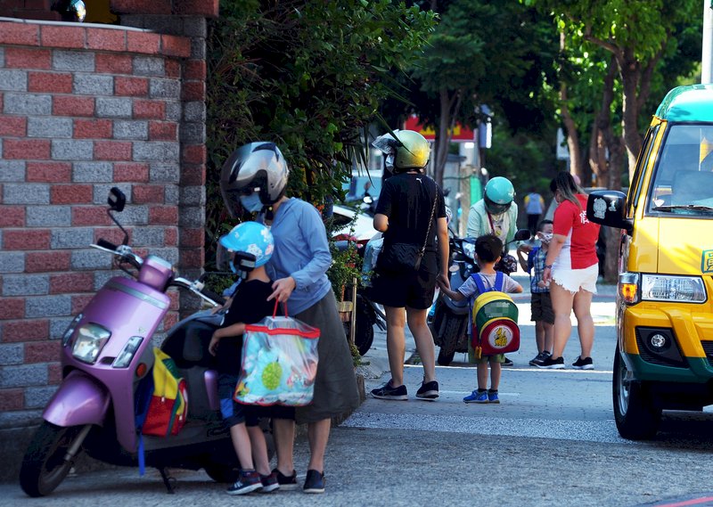 國內COVID-19疫情趨緩,中央宣布27日全國疫情警戒降為二級,桃園市一間幼兒園恢復到校上課,老師與家長一起把小朋友帶進園內。 (圖:中央社)
