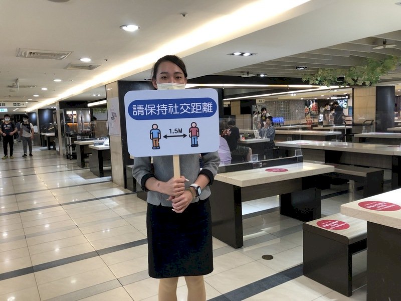 全國COVID-19疫情警戒27日降為2級,台中市有限制開放餐飲內用,百貨公司美食街除設隔板,也有加派人員提醒民眾保持社交安全距離。(業者提供) (圖:中央社)