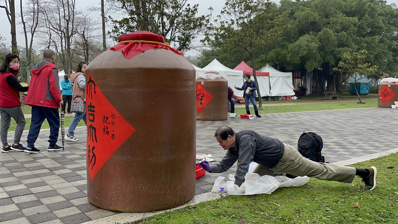 農曆春節將至,金門縣林務所今年再度攜手金門縣書法學會,邀請書法家們在廢棄大酒甕上揮毫寫下新春賀詞, 60個大酒甕就放在森林公園大道兩旁,書法家們或坐或跪或趴,賣力完成各自傑作。前右為退役將軍鄭有諒。中央社記者黃慧敏攝 112年1月14日 (圖:中央社) 農曆春節將至,金門縣林務所今年再度攜手金門縣書法學會,邀請書法家們在廢棄大酒甕上揮毫寫下新春賀詞, 60個大酒甕就放在森林公園大道兩旁,書法家們或坐或跪或趴,賣力完成各自傑作。前右為退役將軍鄭有諒。中央社記者黃慧敏攝 112年1月14日 (圖:中央社)