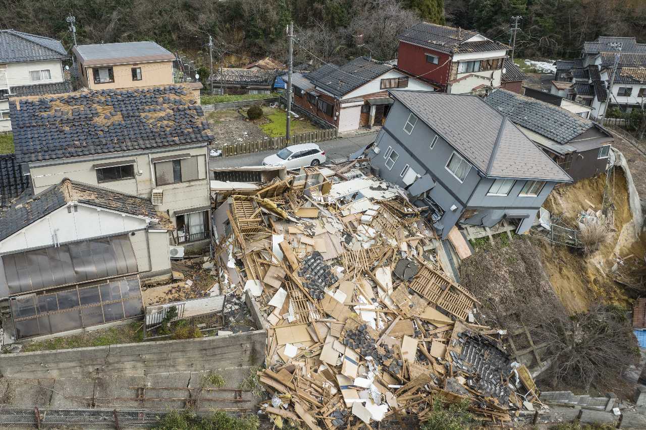 日本石川縣能登地方發生7.6強震，圖為在輪島市的一條街道上，受損和被摧毀的房屋。(AFP)
